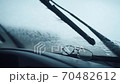 Wipers Clean From Raindrops Car Windshield. In the foreground on the car panel are glasses for vision.. Driving in the rain 70482612