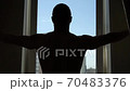 Rear view of a man with short hair standing at home and tight-fitting curtains, silhouette against the window, social distance and self-isolation in quarantine isolation 70483376