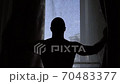 Slow motion shot of a young man opening curtains of seaview window. silhouette 70483377