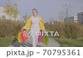 Stylish adult woman is enjoying her purchases while walking with colorful bags on city street. 70795361