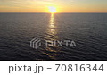Flying over sea or ocean surface during sunset. Setting sun is reflected in the water to form a golden path. Aerial drone shot 70816344