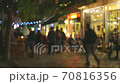 Evening street in the old town with numerous cafes and restaurants. People chat, eat and drink while sitting at cafe tables on summer terraces. Evening city illumination and comfort. Blurred out of 70816356