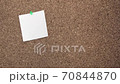 A young white woman pins a second white paper to the notes on a corkboard 70844870