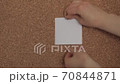 A young Caucasian woman pins a white paper to the notes on a corkboard 70844871