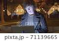 Hipster typing on laptop in the park at night 71139665