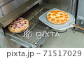 Cook pulls out a pizza of the oven using a shovel 71517029