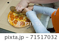 The girl cuts the cooked pizza using a circular knife, adult help her 71517032