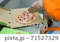 The girl cuts the cooked pizza using a circular knife, adult help her 71527329