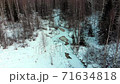 Aerial view: Flight over the winter river and forest. Snow covered trees. Winter landscape, nature, sun rays. River in ice 71634818