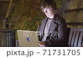 Hipster typing on laptop in the park at night 71731705