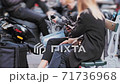 Smartphone use. Unrecognized girls sit on street bench and use smartphones for social media. 71736968