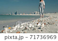 An unrecognized young girl in sunglasses walks along the beach against a backdrop of beautiful 71736969