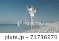 Young attractive blonde girl does yoga on the beach against the backdrop of skyline. Dubai Arabian 71736970