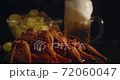 Close up view of lobsters with foamy bear pouring in glass and crisp chips on background in slow motion 72060047