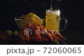 Close up view of lobsters with foamy bear pouring in glass and crisp chips on background in slow motion 72060065
