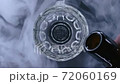 Top close up view of beer is pouring from the bottle into glass with cold smoke in background in slowmotion in 4k resolution. Cold lager beer with foam and bubbles 72060169