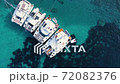 Four yachts anchoring in crystal clear turquoise water while people are working on the boat. 72082376