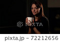 Portrait of a brunette woman with natural beauty. He is in the Studio on a dark background and drinks from a white Cup. 72212656