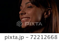 Portrait of a close-up face of a young beautiful brunette woman, with natural beauty. Located in the Studio on a black background. She smiles. 72212668