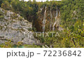 People walk on boardwalk near rock towards waterfalls. Plitvice Lakes from above, Croatia 72236842