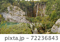 Tourists on wooden path leading to high waterfall. Plitvice Lakes from above, Croatia 72236843