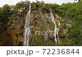 Streams of water fall from sharp rock in green forest. Cloudy day in Croatia 72236844