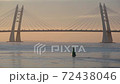 A cable-stayed bridge of Western High-Speed Diameter with traffic, over water partly covered with ice against sunset sky. Beautiful tranquil urban seascape in Saint Petersburg, Russia. 72438046
