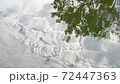 Tree and cloudy sky reflection in the clear water of a lake 72447363