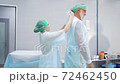Doctors team help wearing medical uniform to each other, prepare for operation. 72462450