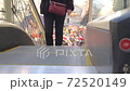 A brunette woman, in a dark jacket, climbs the escalator in the mall. 72520149
