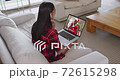 Mixed race woman on laptop video chat wearing wireless earphones during christmas at home 72615298