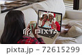 Mixed race woman on laptop video chat having coffee during christmas at home 72615299