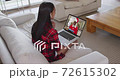 Mixed race woman on laptop video chat wearing wireless earphones during christmas at home 72615302