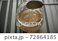 Natural honey is poured from a spoon into a jar 72864185