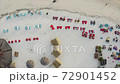 Top aerial view of sandy beach, straw umbrellas and roofs of small cabins at resort, tourists enjoy the evening in comfortable armchairs. GILI AIR Air island, Indonesia 72901452