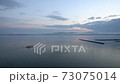 朝焼けの海に浮かぶ漁船 73075014