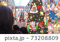 middle-aged women, Caucasoid, brunette in dark jacket, taking pictures on smartphone in shopping mall christmas decorations 73208809