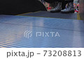 Escalator in a shopping center is moving. Close-up of feet of people who climb the steps 73208813