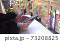 hands of a middle-aged woman, brunette prints on a smartphone in a shopping mall 73208825