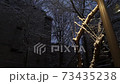Silhouette-like buildings and glowing pillars and trees on a snowy evening 73435238