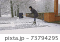 Woman shoveling snow on sidewalk 73794295