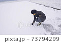 Happy woman enjoy first snow rolling snowball to make snowman 73794299