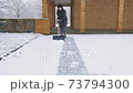 Woman removing snow from sidewalk 73794300