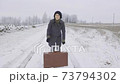 Woman hitchhiker with heavy vintage suitcase 73794302