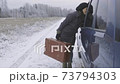 Woman hitchhiker with vintage suitcase talking with driver 73794303