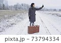 Woman hitchhiker holding up smartphone trying to get a signal 73794334