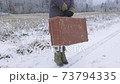 Woman with vintage suitcase on road in winter 73794335
