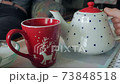 Pouring hot tea in a red cup with a teapot 73848518