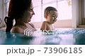 Mother and happy baby smiling splashing water in indoor pool 73906185