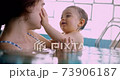 Mother and happy baby touching face smiling in indoor pool 73906187